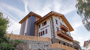 Un hôtel à la façade en pierre, doté de balcons en bois et d’une enseigne.