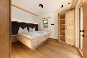 A bedroom with a wooden bed, built-in wardrobe, and a window with a view.