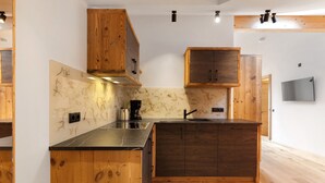 A modern kitchen with wooden cabinets, a marble backsplash, and a built-in island. - Apartment 'Panorama Loft Meran' with Mountain View, Private Terrace and Wi-Fi (Fié allo Sciliar)