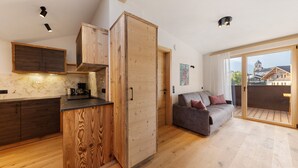 A modern kitchen with wooden cabinetry and a dining area with a sofa. - Apartment 'Panorama Loft Meran' with Mountain View, Private Terrace and Wi-Fi (Fié allo Sciliar)
