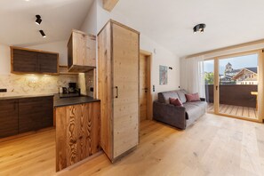 A modern kitchen with wooden cabinetry and a dining area with a sofa.
