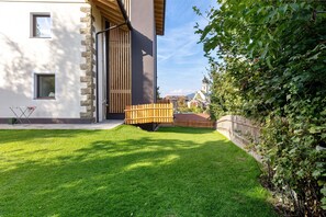 Een modern gebouw met een stenen gevel, een houten terras en een verzorgd gazon.