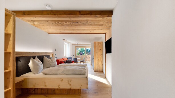 A modern bedroom with a wooden ceiling, a bed with pillows, and a TV mounted on the wall. - Studio Apartment 'Gardena' with Mountain View, Shared Garden and Wi-Fi (Fié allo Sciliar)
