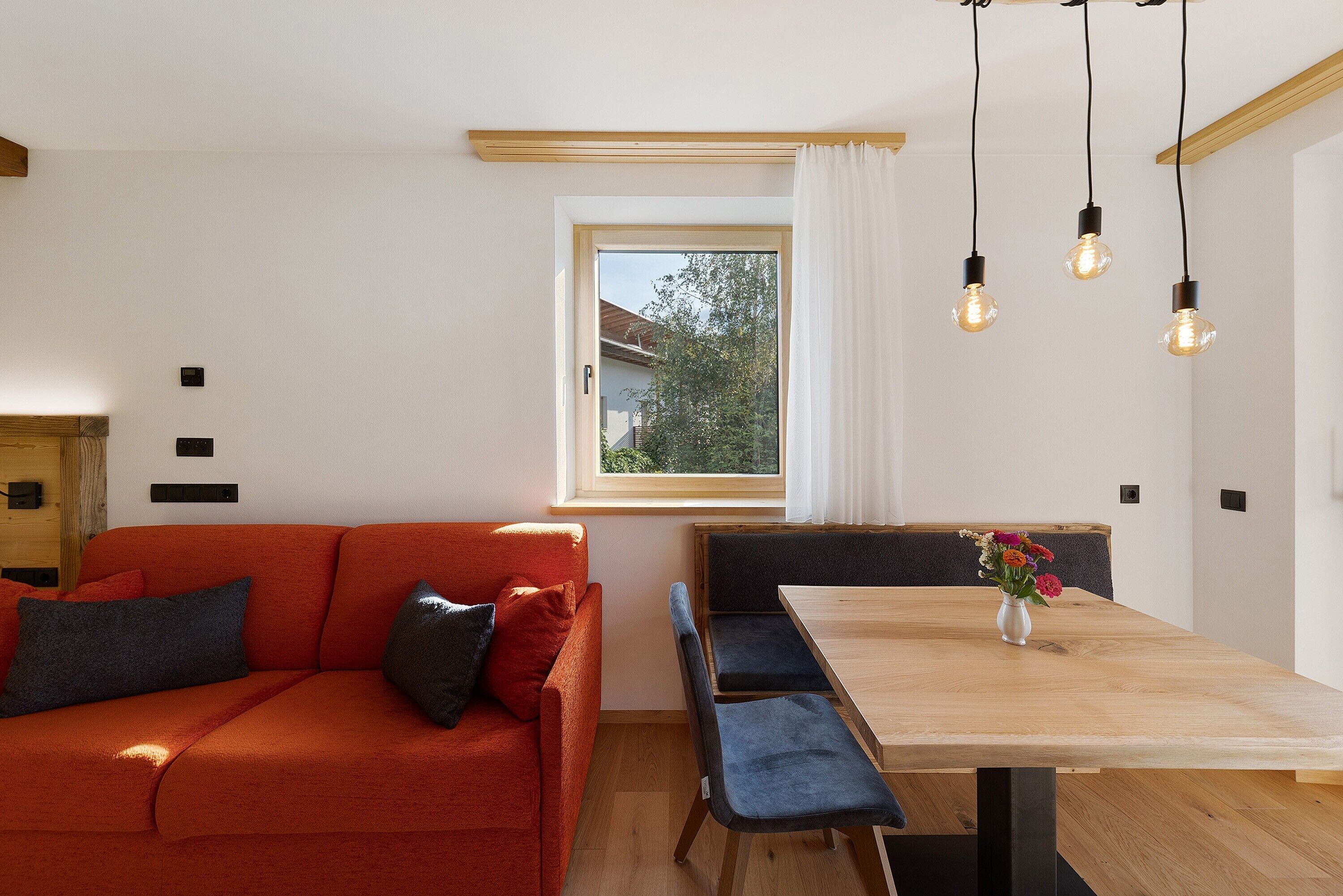 Un espacio moderno para vivir con sofá, mesa de comedor y ventana con cortinas.