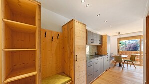 Un intérieur en bois comprenant un banc, des placards et un coin repas avec des chaises.