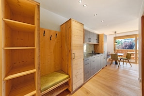 A wooden interior with a bench, cabinets, and a dining area with chairs.