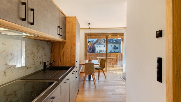 Une cuisine moderne dotée d’un îlot central, de meubles en bois et donnant sur l’espace repas.