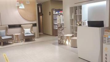A hotel lobby with seating areas, a reception desk, and a self-service kiosk.