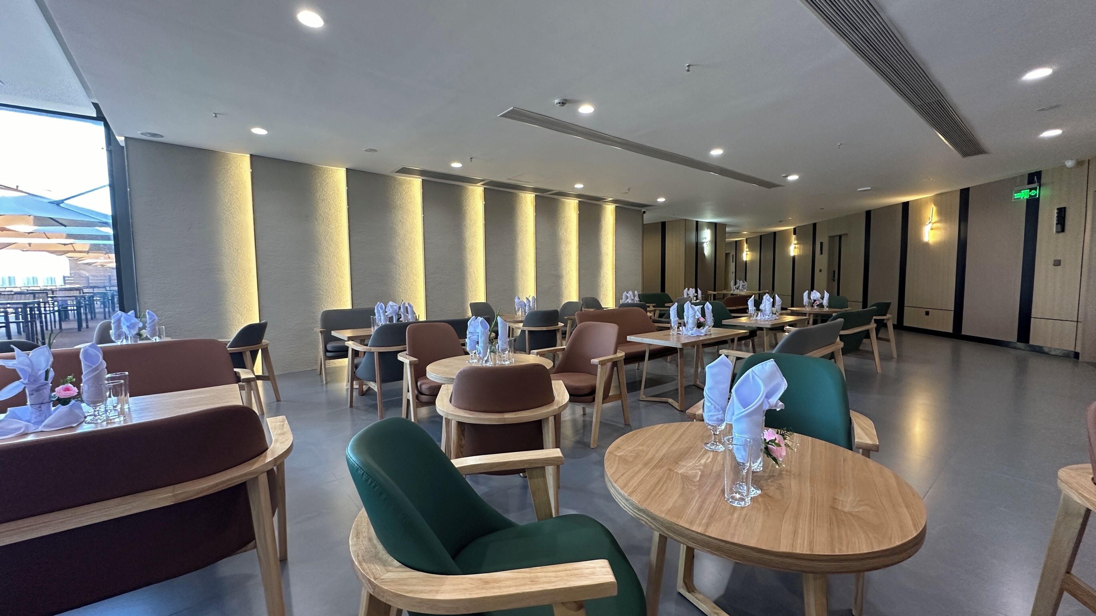 A modern dining area with round tables and chairs, equipped with napkins and glasses.