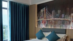 A hotel room with a large bed, a view of a cityscape through a window, and a painting of a bridge on the wall. - Fan's Hotel Palo (Palo)