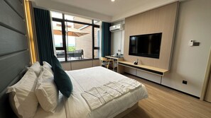 A modern hotel room with a large bed, a desk, a flat-screen TV, and a view of the outdoors. - Fan's Hotel Palo (Palo)