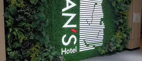 A wall with a green plant wall and a logo for 'FANS Hotel'.
