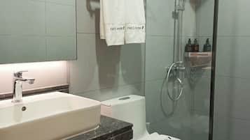 Une salle de bain moderne avec un grand lavabo, des toilettes, une douche en verre et un porte-serviettes sur lequel sont disposées des serviettes étiquetées « Hôtel FAN’S ».