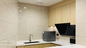 A modern kitchen with a built-in sink, a black range hood, and light wood cabinetry. - Fan's Hotel Palo (Palo)