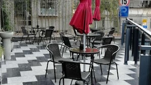 An outdoor seating area with round tables and chairs, a checkered floor, and a red umbrella. - Cui Zhu Hotel (Shenzhen)