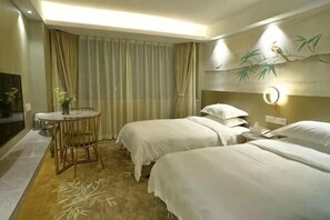 A hotel room with two beds, a small table with a chair, a round mirror, and a wall-mounted lamp.