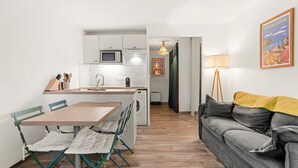 Un espacio habitable compacto con kitchenette, comedor y sofá.