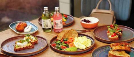 A table with various dishes including toast, scrambled eggs, and a salad, along with two bottles of drinks.