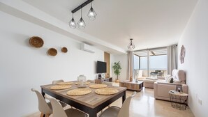 Una sala de estar moderna con comedor, sofá, televisión y un amplio ventanal.