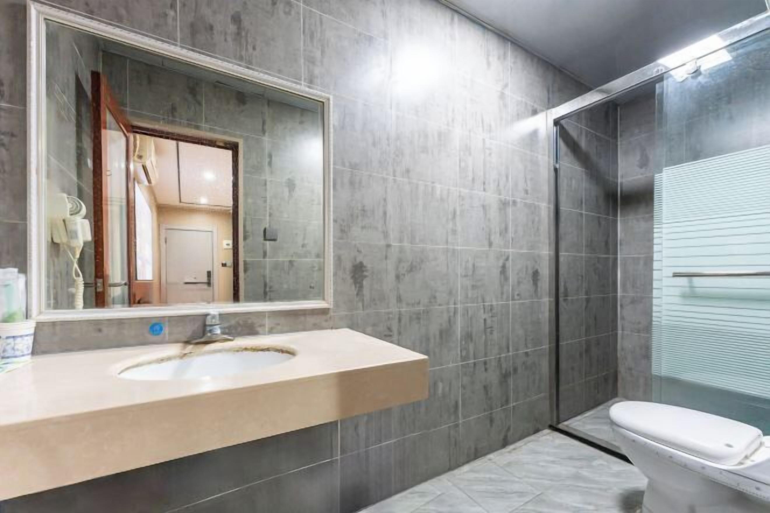 Un baño moderno con un espejo grande, un lavamanos y un inodoro.