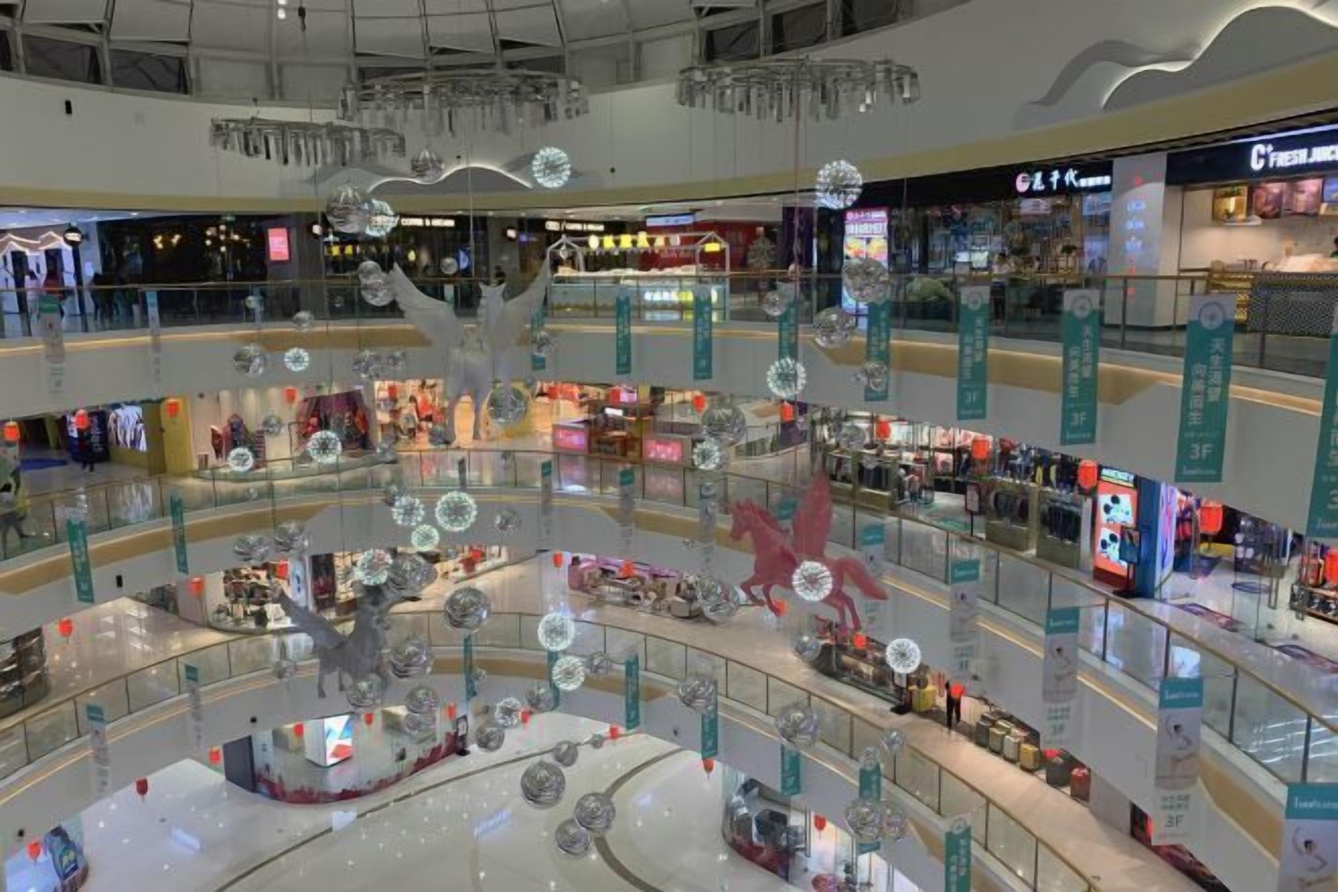 Un centro comercial de varios niveles con diversas tiendas y una zona decorativa central con adornos esféricos.