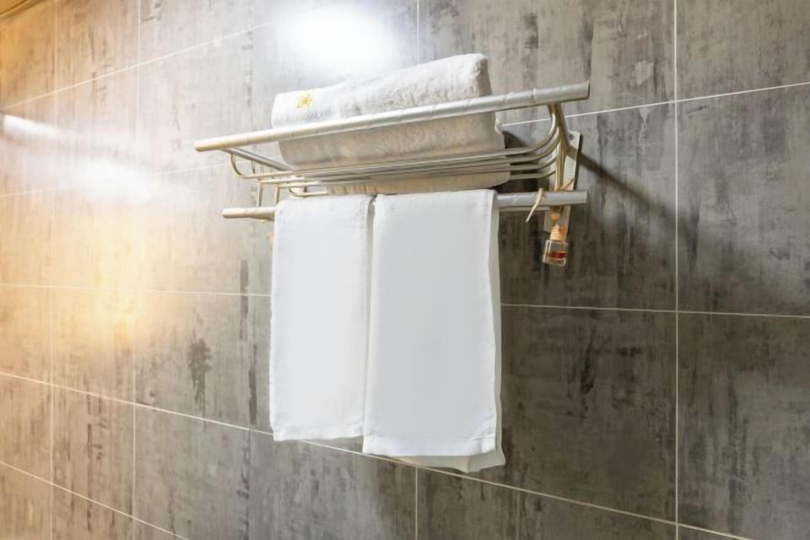 A bathroom with a towel rack holding two white towels.