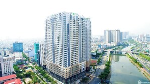 A high-rise building with a grid of windows and a green logo on the top.