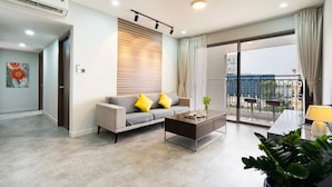 A modern living room with a sofa, coffee table, and a balcony with a view.