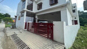 Un edificio moderno de dos pisos, con una reja roja y un automóvil estacionado en el interior.