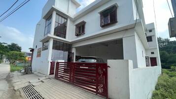 A modern two-story building with a red gate and a car parked inside.