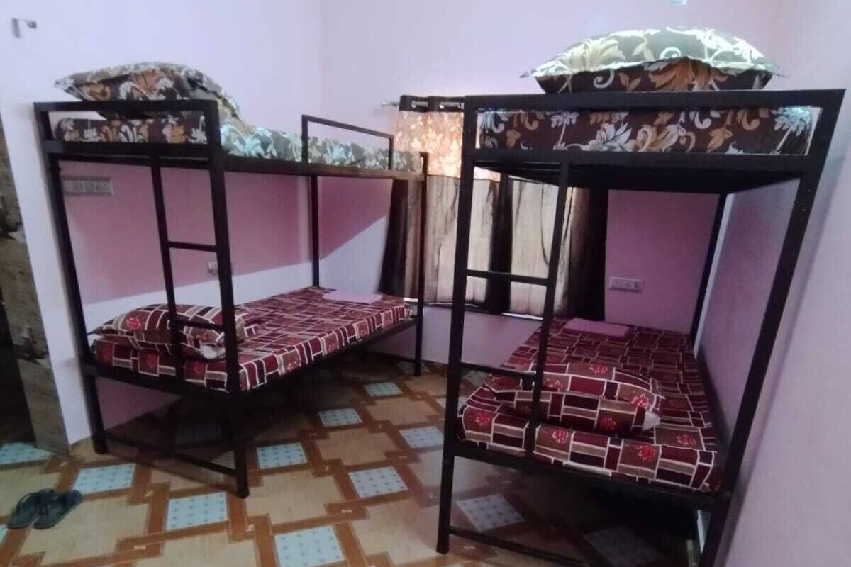 Une chambre avec des lits superposés, des carreaux de sol à motifs et une fenêtre avec des rideaux.