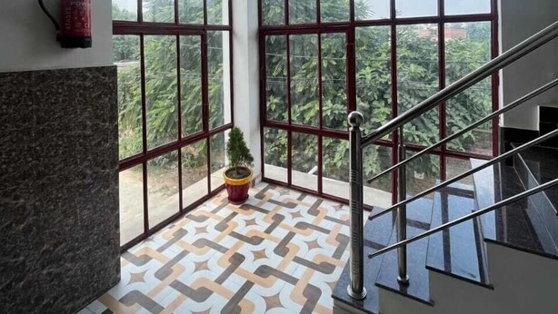 Una habitación amplia con ventanas grandes, un extintor, una planta en maceta y un piso con diseño.