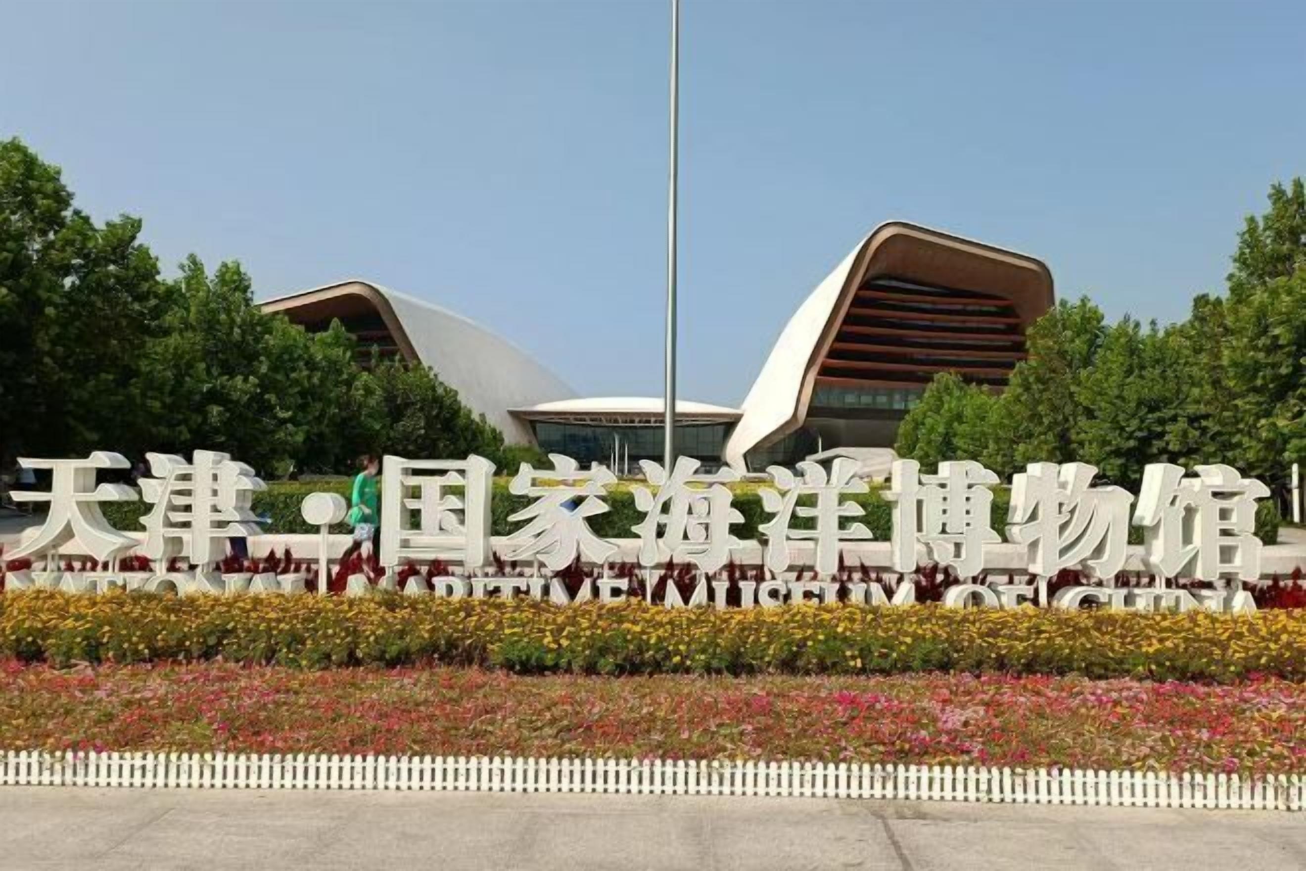 A modern building with a unique architectural design, surrounded by a well-maintained garden with colorful flowers.