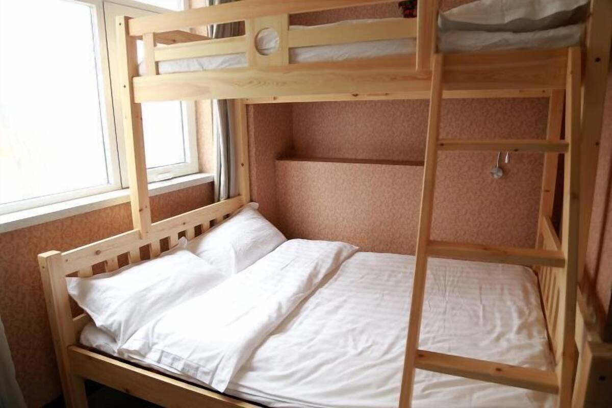 Una cama individual con ropa blanca, una ventana y una pared cubierta de alfombra.