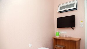 Una habitación de hotel con cama, un escritorio de madera, televisor y ventana.