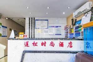 A hotel reception area with a marble counter, informational posters, and a seating area. - Tianjin Liansong Hotel (Tianjin)