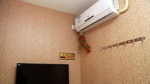 Una habitación con televisor de pantalla plana, aire acondicionado, una guirnalda decorativa y una placa en la pared.