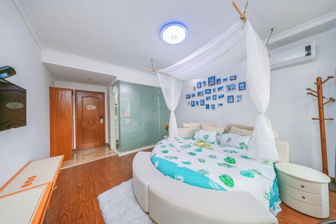 Een slaapkamer met een hemelbed, een nachtkastje, een aan de muur bevestigde televisie en een deur naar een andere kamer.