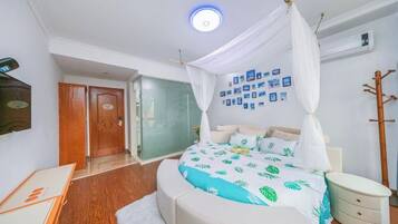 Een slaapkamer met een hemelbed, een nachtkastje, een aan de muur bevestigde televisie en een deur naar een andere kamer.