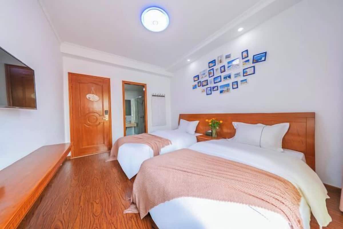 Une chambre d’hôtel avec deux lits, un plancher en bois, un téléviseur à écran plat et un mur orné de tableaux.