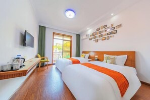 Een hotelkamer met twee bedden, een bureau met een waterkoker, een televisie en een muur met ingelijste foto's.