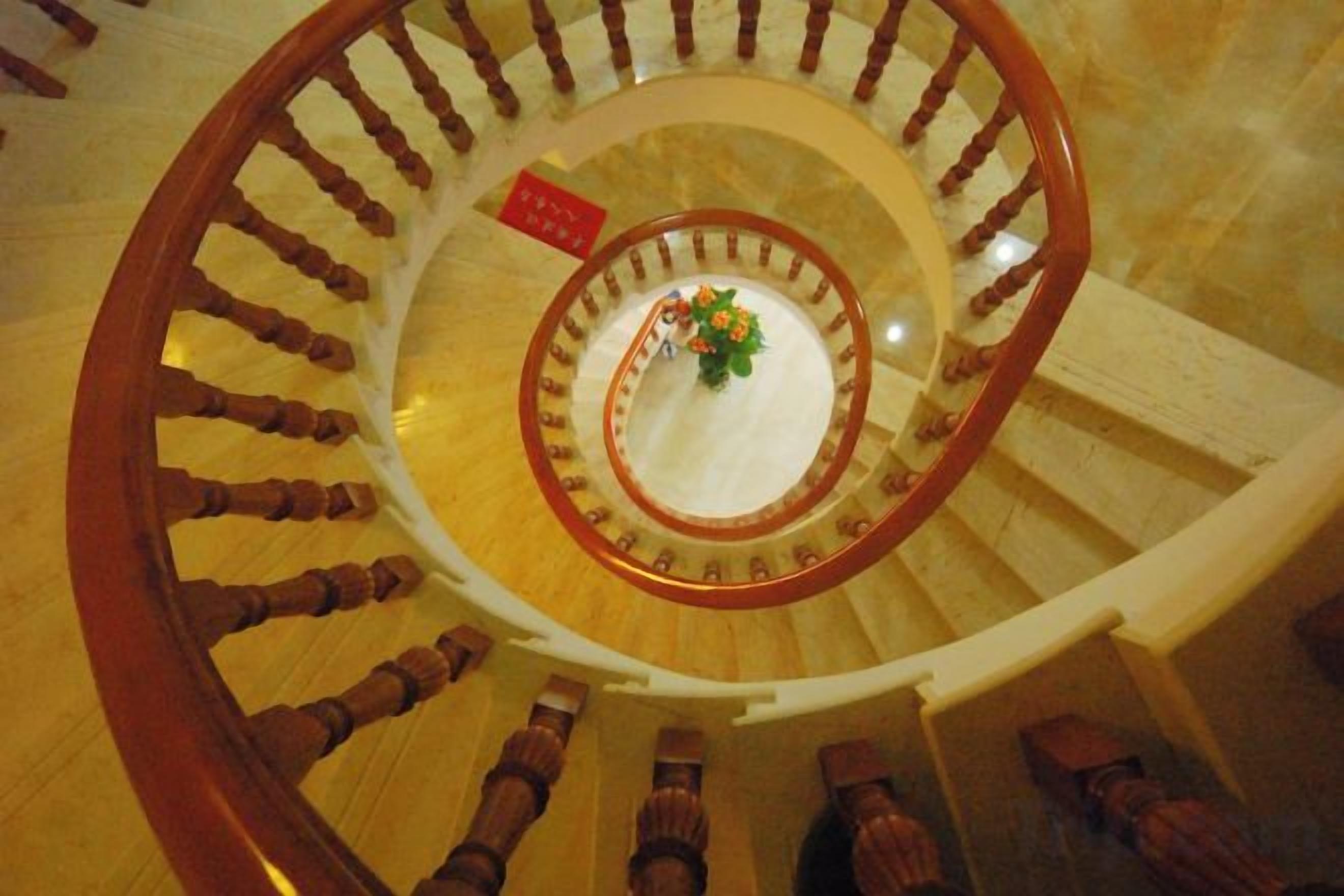 A spiral staircase with wooden handrails and steps, leading to an upper floor.