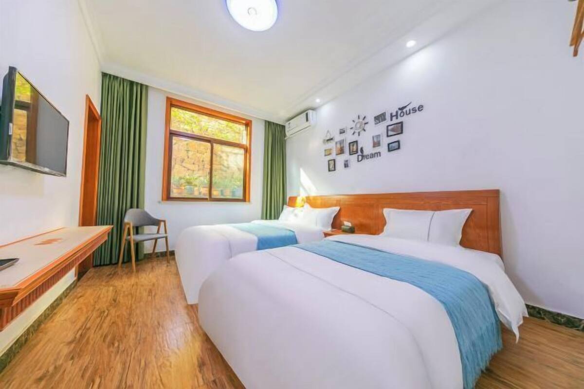 Une chambre d’hôtel avec deux lits, un bureau, une chaise et une télévision.