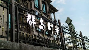 Un bâtiment doté de grilles en fer forgé décorées et d’une enseigne avec des caractères chinois.