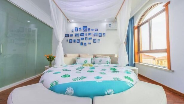 Une chambre à coucher avec un lit à baldaquin, un mur recouvert de photos encadrées et une grande fenêtre.