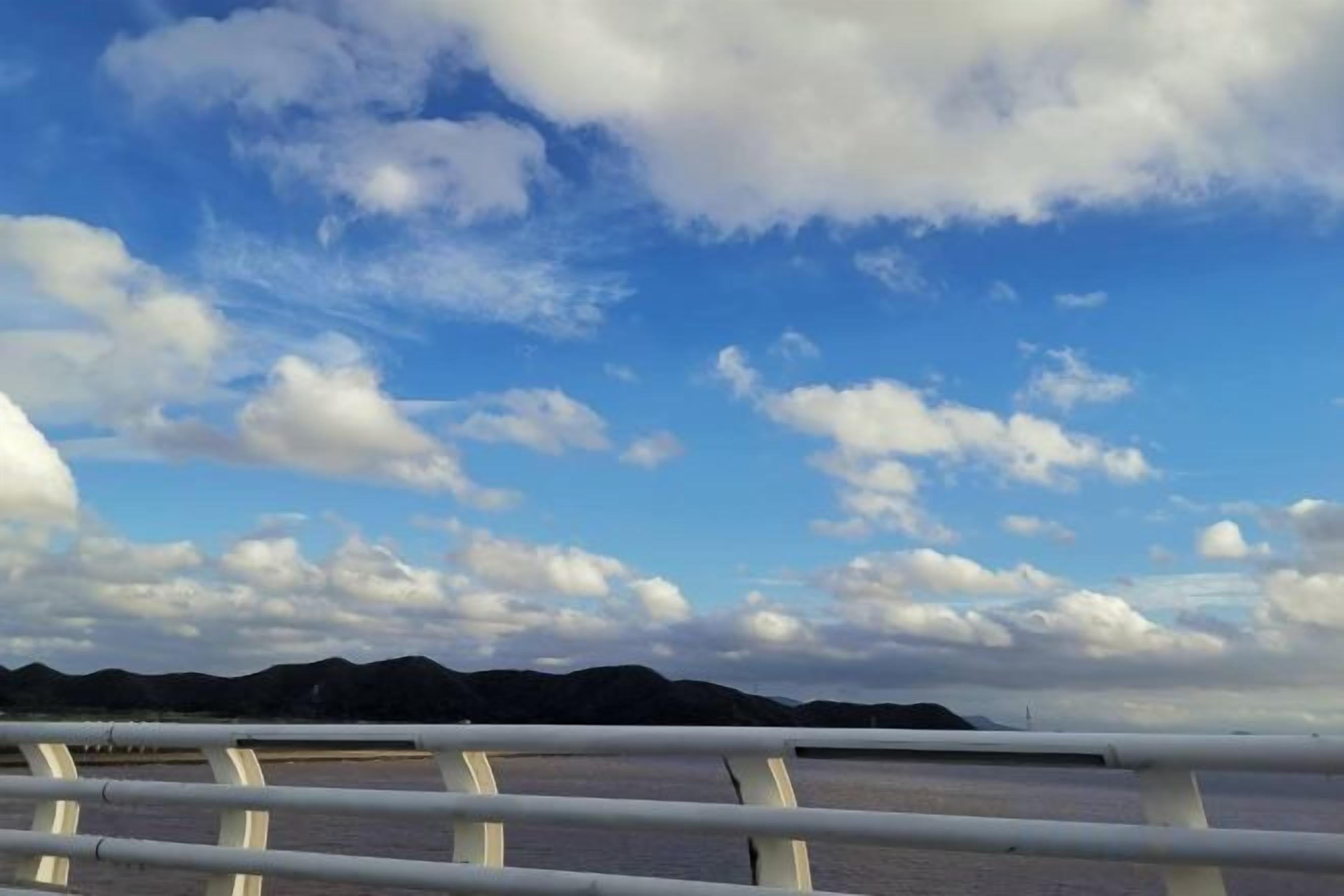 Ένας καθαρός ουρανός με σύννεφα και μια ορεινή αλυσίδα στο βάθος.