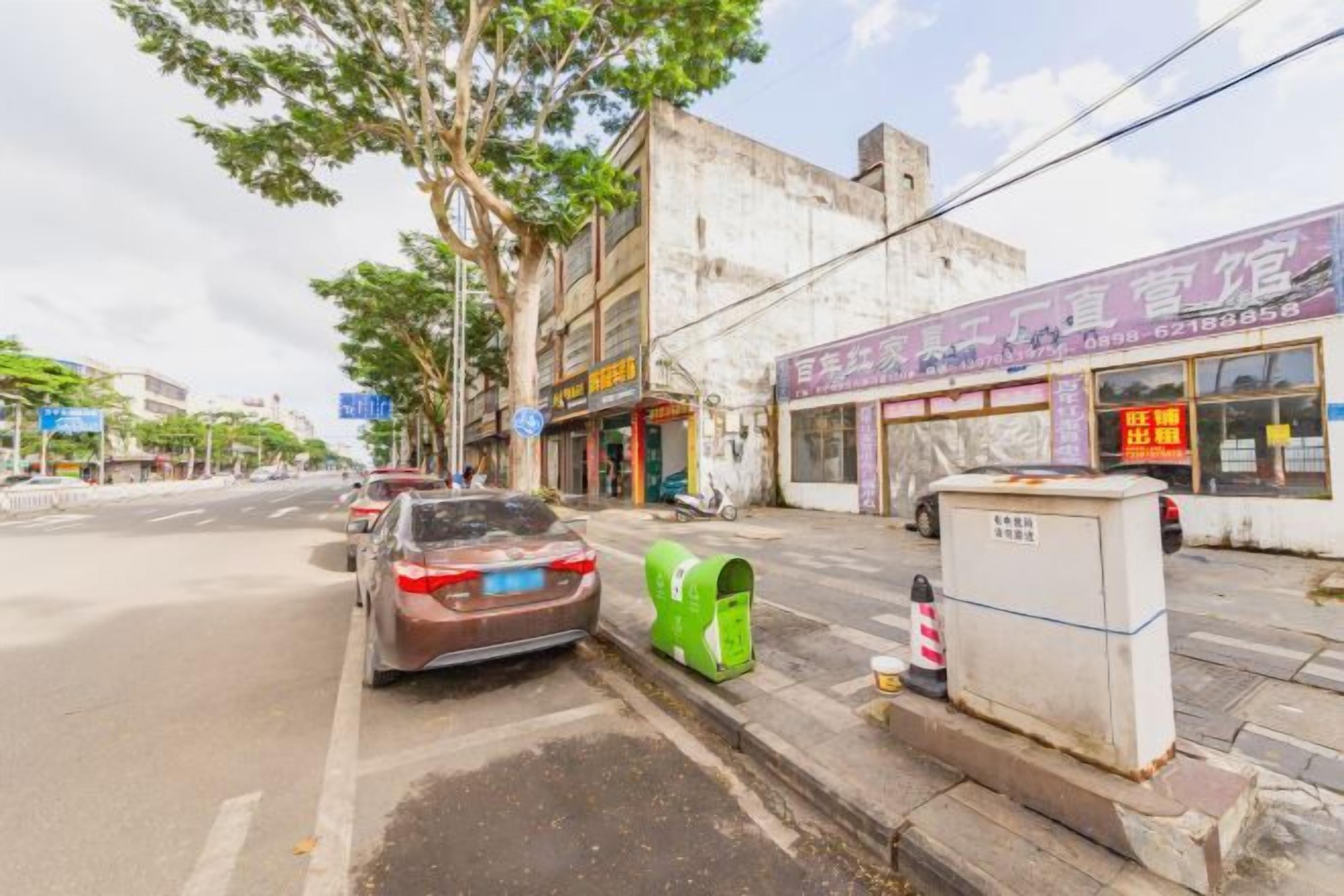 A street view with a parked car, a mailbox, and a building with a sign.