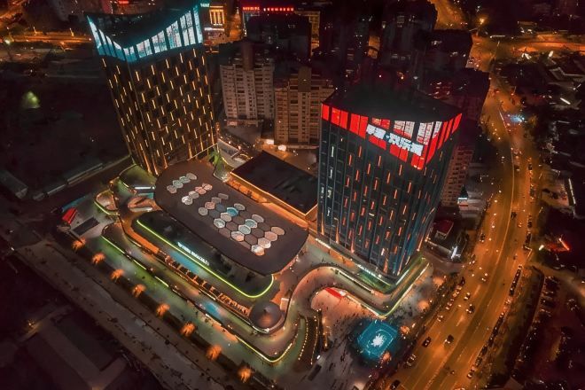 A modern building with a unique geometric design, featuring a central courtyard with a patterned floor and surrounding structures.