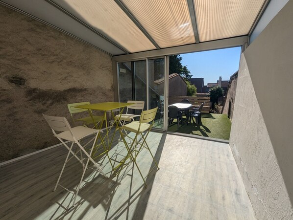 A modern patio with a glass door leading to a garden, featuring a table and chairs. - In the heart of the historic city of Langres, a city of art and history. (Langres)