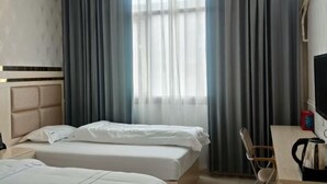 A hotel room with two beds, a desk with a chair, a television, and a window with curtains. - Ce Heng Hengjie Business Hotel (Ceheng)